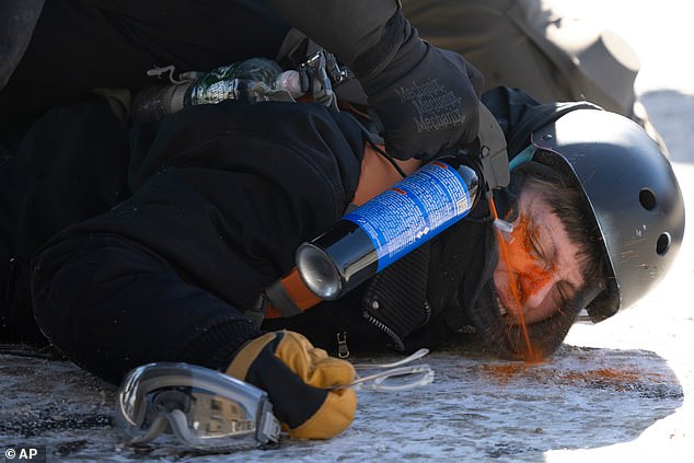 A protester is pepper sprayed at close range while being detained near the site of the fatal shooting of 37-year-old Alex Pretti by federal agents in Minneapolis on Saturday