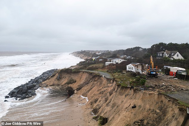 Properties being demolished close to the cliff edge at Hemsby in Norfolk which are at risk of collapse as high tides cut into sandy cliffs
