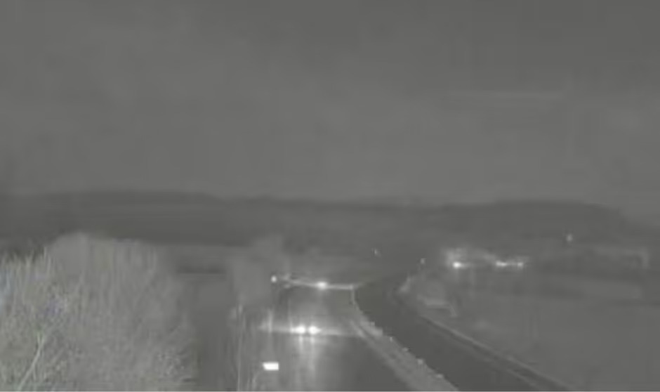 Night-time view of the M5 Motorway closed due to flooding from Storm Chandra, showing car headlights on the wet road.
