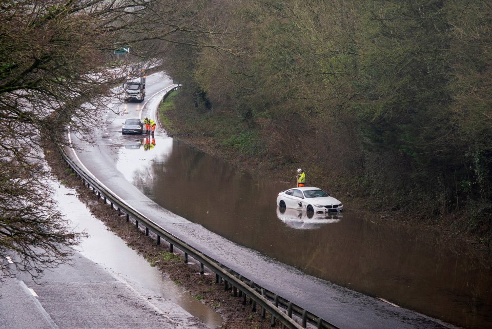 A white car is stuck in floodwater on the A30 near Honiton, Devon.