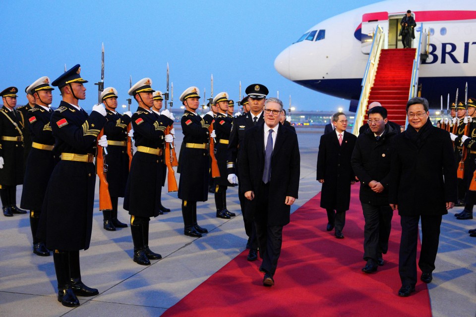 British Prime Minister Keir Starmer and Chinese Finance Minister Lan Foan walk on a red carpet while soldiers stand at attention.