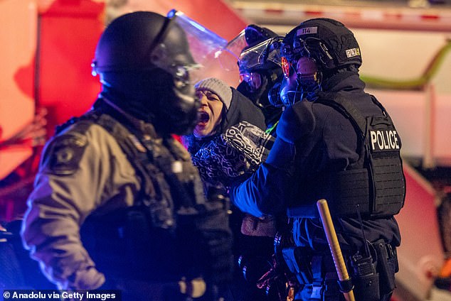 Protesters clash with law enforcement while holding a 'noise demonstration' outside of a hotel believed to be housing federal immigration agents near Minneapolis, on Monday