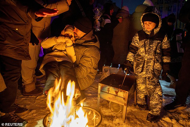 People warm themselves at a bonfire at a party with DJ and food at a sports ground in a neighborhood left without electricity after recent Russian strikes on the capital's civilian infrastructure, amid Russia's attack on Ukraine, during sub-zero temperatures in Kyiv, Ukraine January 24, 2026