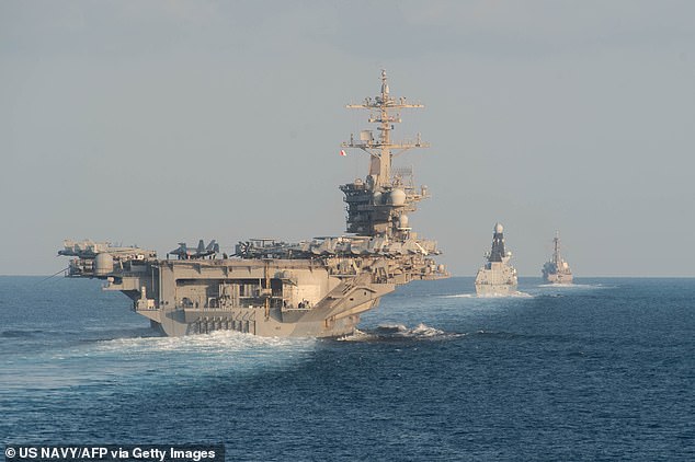 The USS Abraham Lincoln aircraft carrier (L) transits the Strait of Hormuz on November 19, 2019. The US naval strike group led by the USS Abraham Lincoln aircraft carrier has deployed to Middle Eastern waters