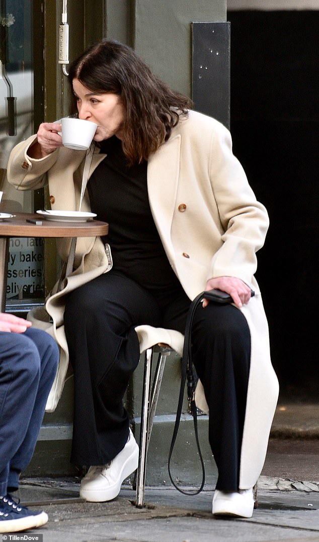 Styling her shoulder length brunette tresses loose, Nigella sipped on her hot beverage while sitting outside a cafe with her male friend