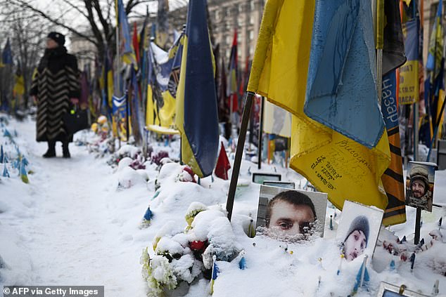 A woman visits the snow-covered memorial for the fallen Ukrainian and foreign fighters on Independence Square in Kyiv