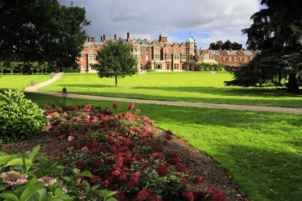 Sandringham House and its gardens, with a path leading to the red brick estate.