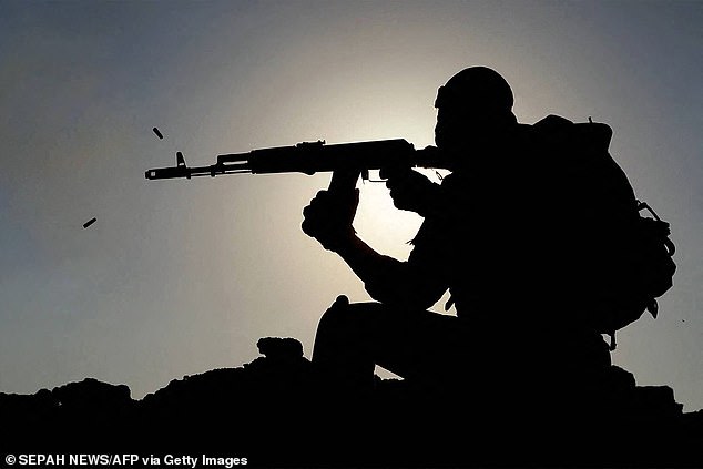 An IRGC soldier firing an assault rifle during a military drill in the Gulf