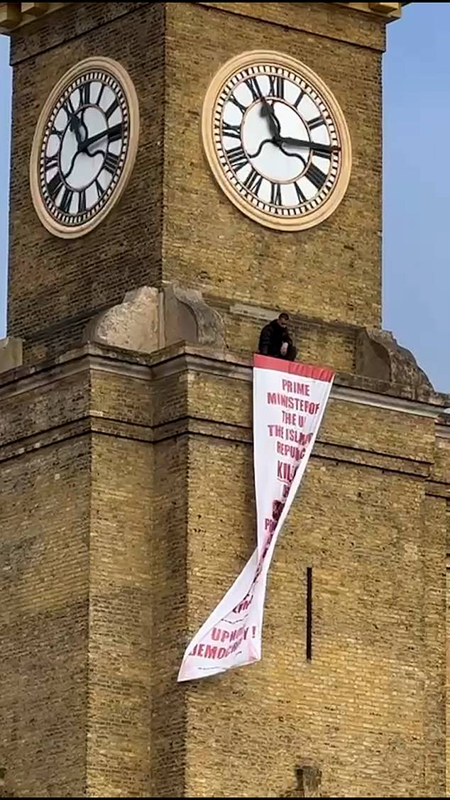 The protester scaled the 120ft landmark at King's Cross Station in central London this morning