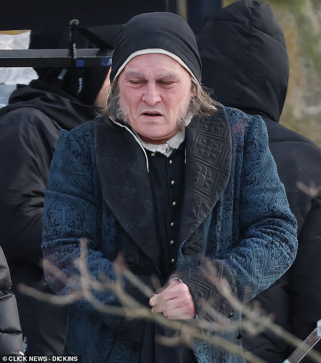 He was dressed in a blue brocade overcoat and black cap, and sporting long grey sideburns