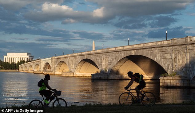 Bicyclists ride along the Mt. Vernon Trail that follows the Potomac River in Virginia near the Arlington Memorial Bridge, with the Lincoln Memorial and the Washington Monument seen in the view