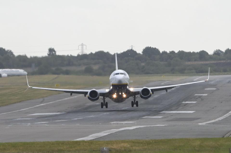 An airplane with its landing lights on approaches a runway at Birmingham Airport in strong crosswinds.