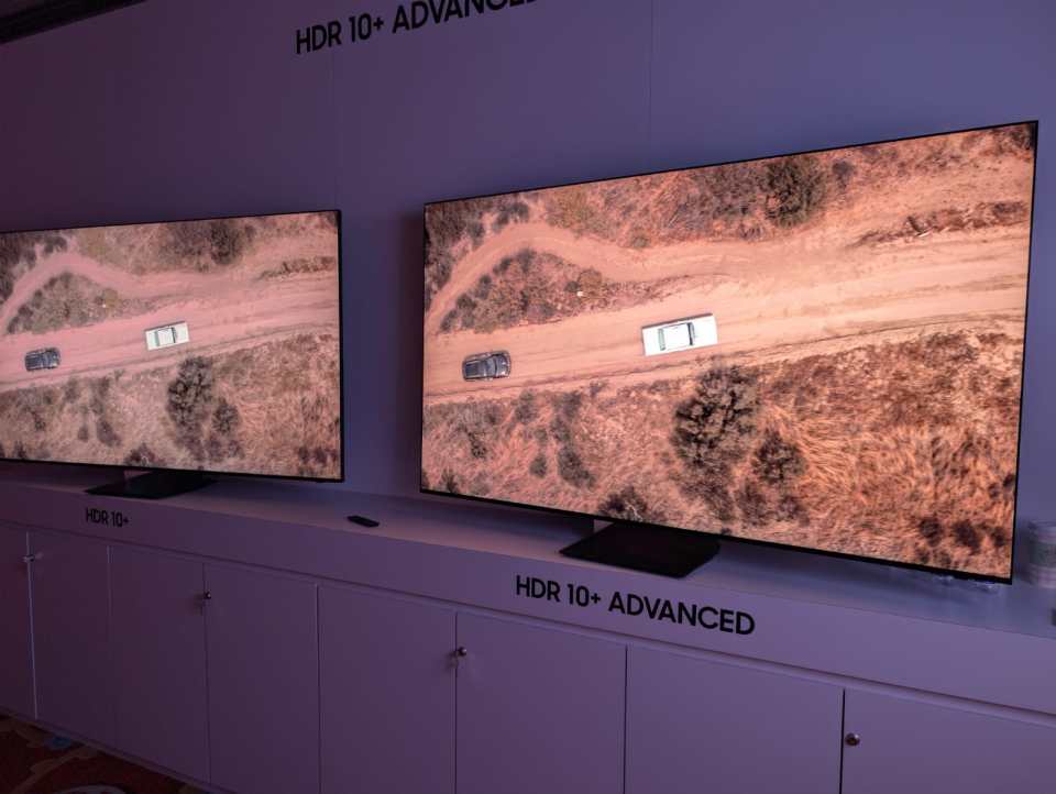 Two televisions display an aerial view of cars on a dirt road, one labeled "HDR 10+" and the other "HDR 10+ ADVANCED."
