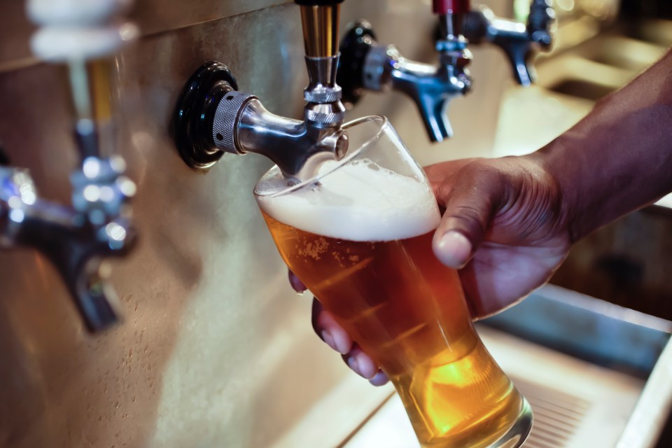 An African American person's hand filling a beer glass at a bar.