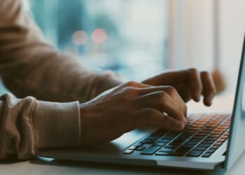 A man works on his laptop at an office desk.