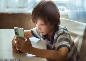 Top doctors have warned that the use of mobile phones among children has become a 'public health emergency'. Stock image shows a child using a mobile phone