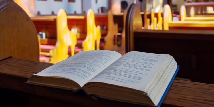 Open Bible is seen in a stock photo on a church pew.