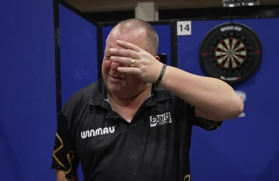 Mervyn King covering his face in exasperation during a darts match.