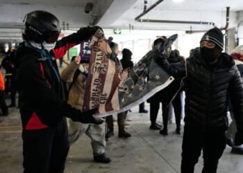 Anti-ICE protesters tear a flag in half in a parking garage on Jan. 17, 2026 in Minneapolis.