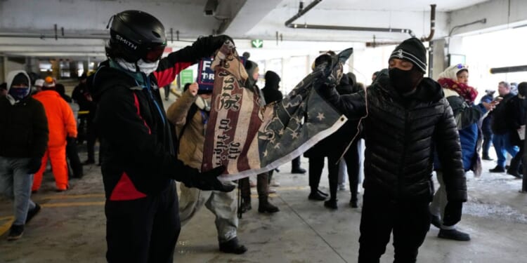 Anti-ICE protesters tear a flag in half in a parking garage on Jan. 17, 2026 in Minneapolis.