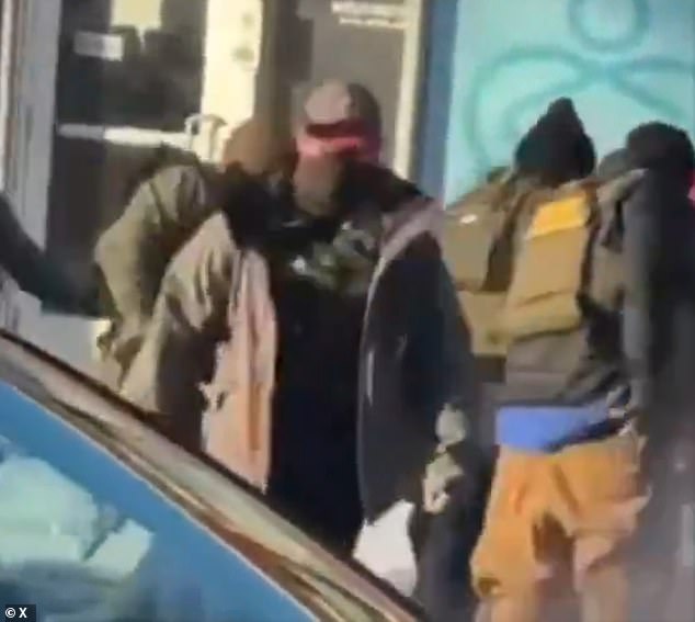 Pictured: This federal agent is seen retreating with what appears to be a firearm that he did not have before reaching down near Pretti's lower back area as he was being held down by officers