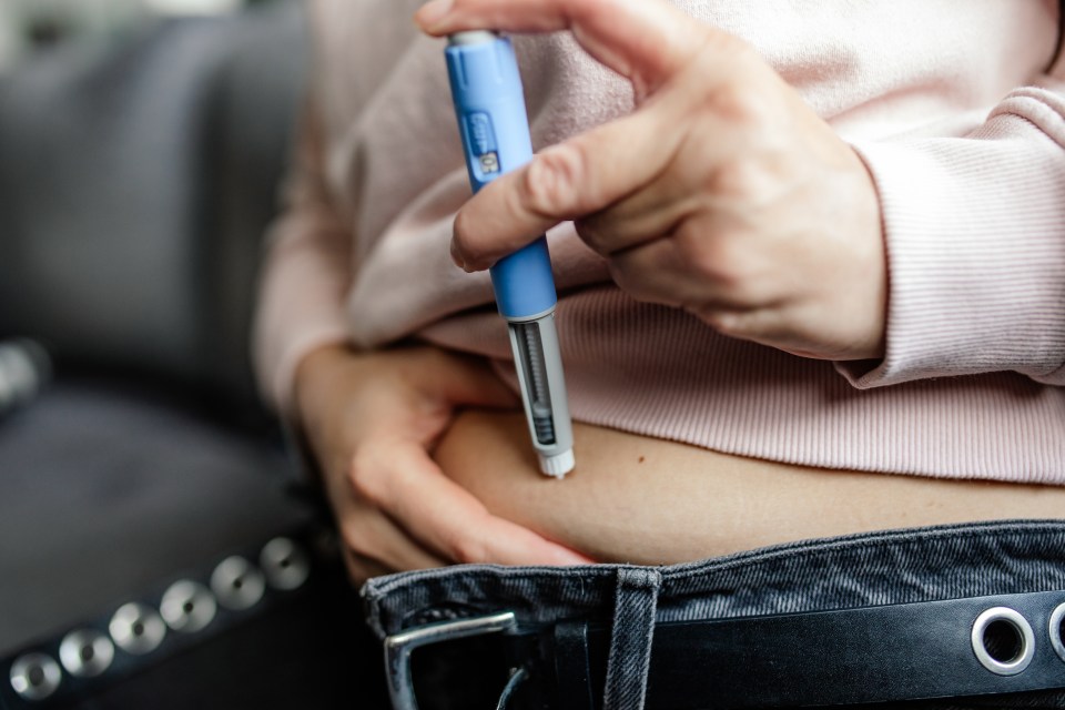A woman self-injects semaglutide into her abdomen using an injection pen for weight loss or diabetes treatment.