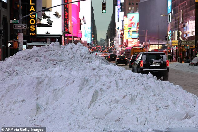 A pile of plowed snow is seen as vehicles make their way through Times Square in New York City on January 26, 2026. A monster storm barreling across the United States had killed at least 11 people on Monday, prompting warnings to stay off the roads, mass flight cancelations and power outages after a weekend of misery. The storm dumped snow, sleet and freezing rain across swathes of the country from Texas to New England, with temperatures set to fall dangerously low this week. (Photo by TIMOTHY A.CLARY / AFP via Getty Images)