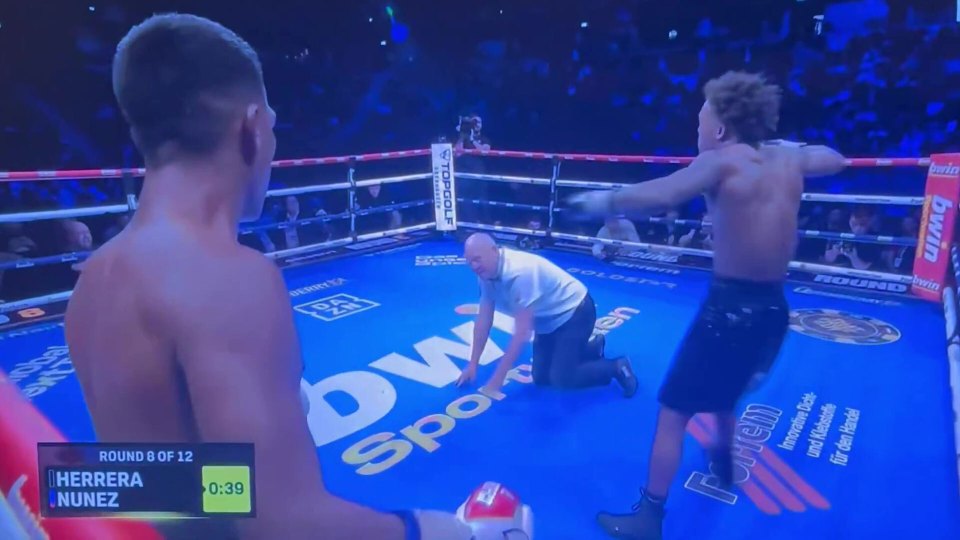 Boxing match between Herrera and Nunez, with the referee on his knees, and the two boxers looking at each other.
