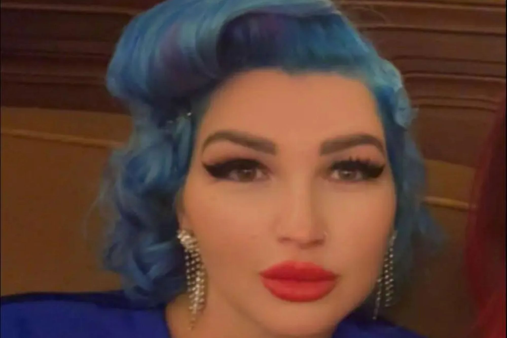 An image collage containing 1 images, Image 1 shows Tania Williams, a woman in her 40s, with vibrant blue hair, a blue top, and red lipstick