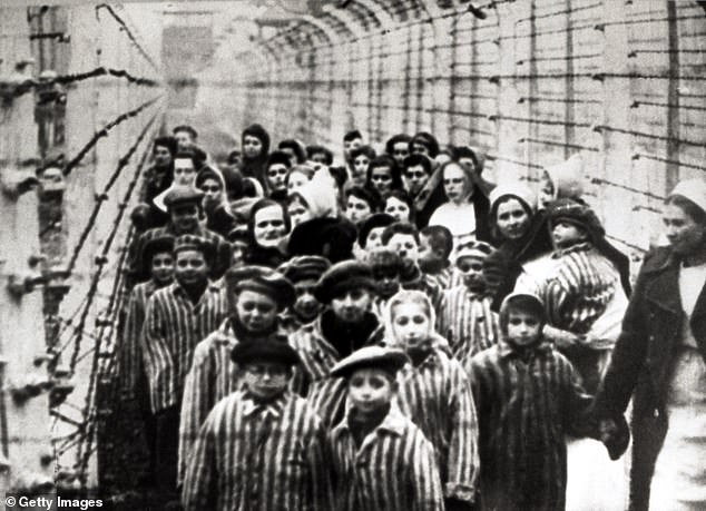 Children pictured behind a barbed wire fence after the liberation of the camp