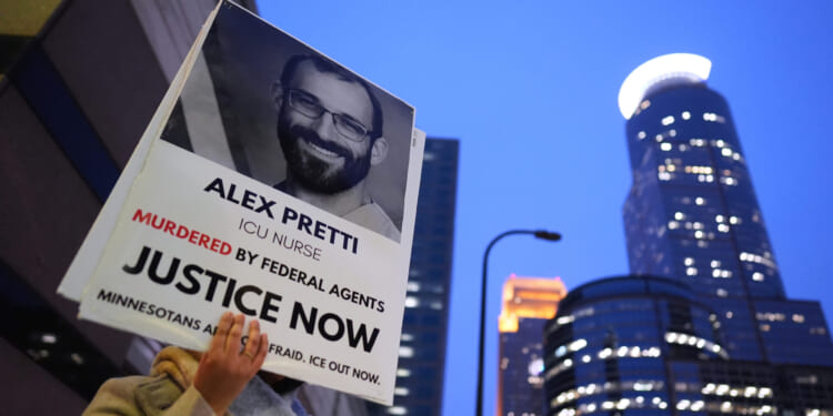 A person holds a sign of Alex Pretti during a protest outside the office of Sen. Amy Klobuchar on Jan. 26, 2026, in Minneapolis, Minnesota.