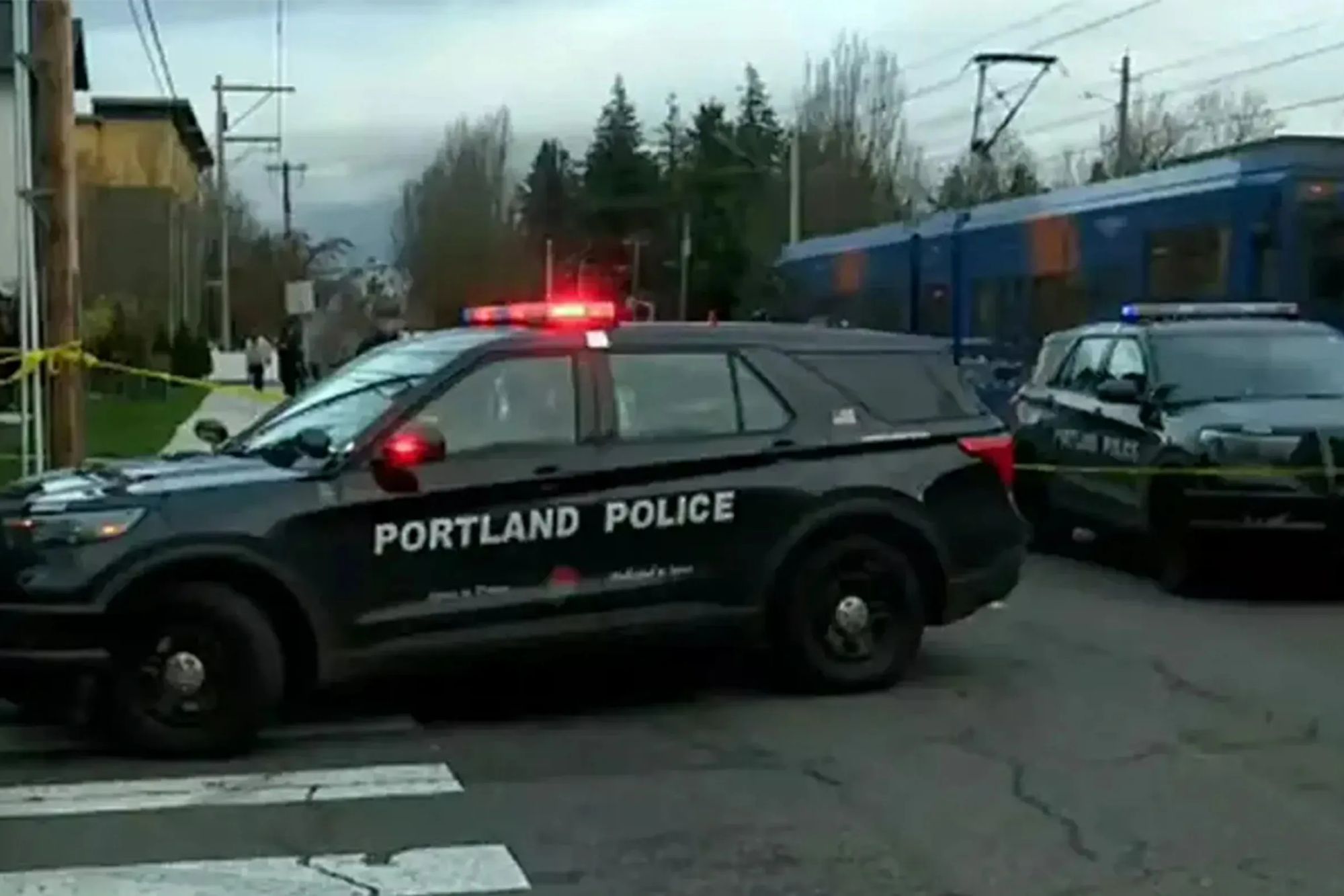 An image collage containing 1 images, Image 1 shows Two Portland Police vehicles parked near a blue train with yellow caution tape marking off the area