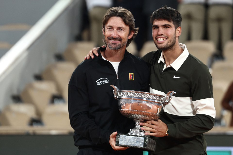 Carlos Alcaraz and coach Juan Carlos Ferrero hold the French Open trophy.