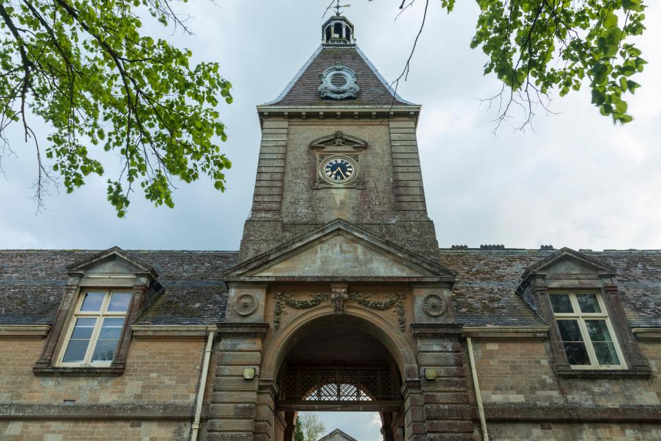 Rendcomb College in the Cotswolds, Gloucestershire, a historic building with a clock tower and arched entryway.