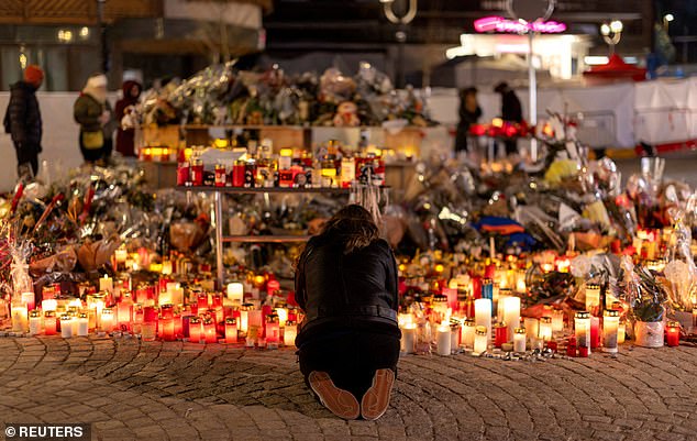 A woman lights a candle at a makeshift memorial outside the "Le Constellation" bar, after a deadly fire and explosion during a New Year's Eve party, in the upscale ski resort of Crans-Montana in southwestern Switzerland, January 5, 2026
