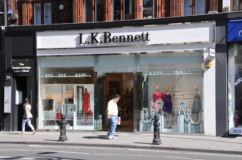 A street-level view of an L.K. Bennett store with window displays featuring shoes, handbags, and mannequins in dresses.