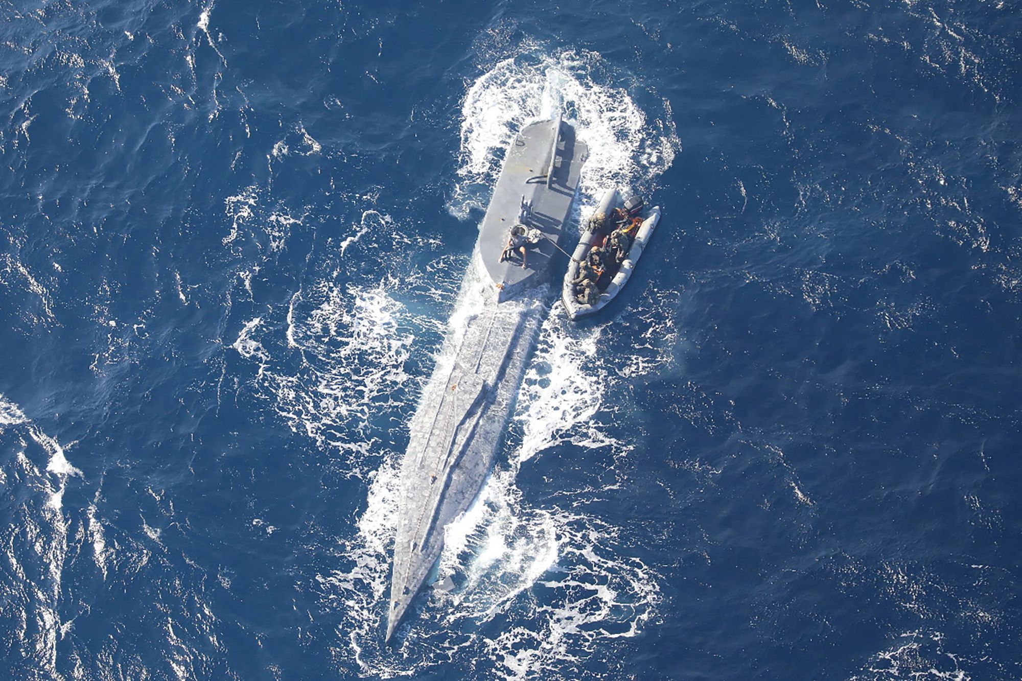 An image collage containing 1 images, Image 1 shows Aerial view of a semi-submersible craft with an inflatable boat alongside it in the open ocean
