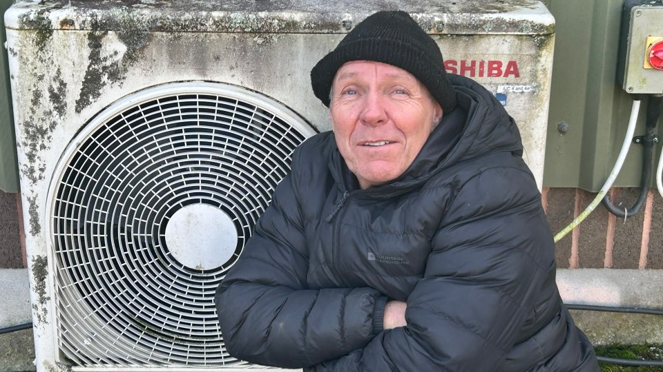 John Frost next to a heat pump.