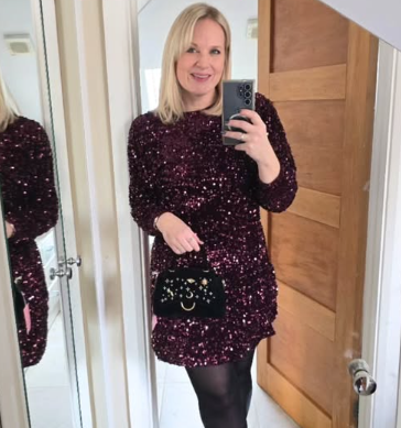 Woman in a sparkly burgundy dress taking a mirror selfie.