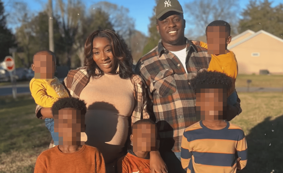 A woman, pregnant, and a man posing with five children.