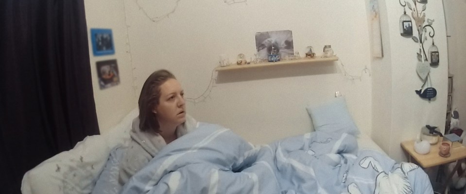 Lucy Letby in bed under a blue comforter looking to the right.