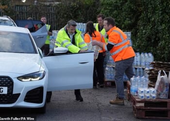 A worker hands out bottled water at the Tunbridge Wells Sports Centre on December 3