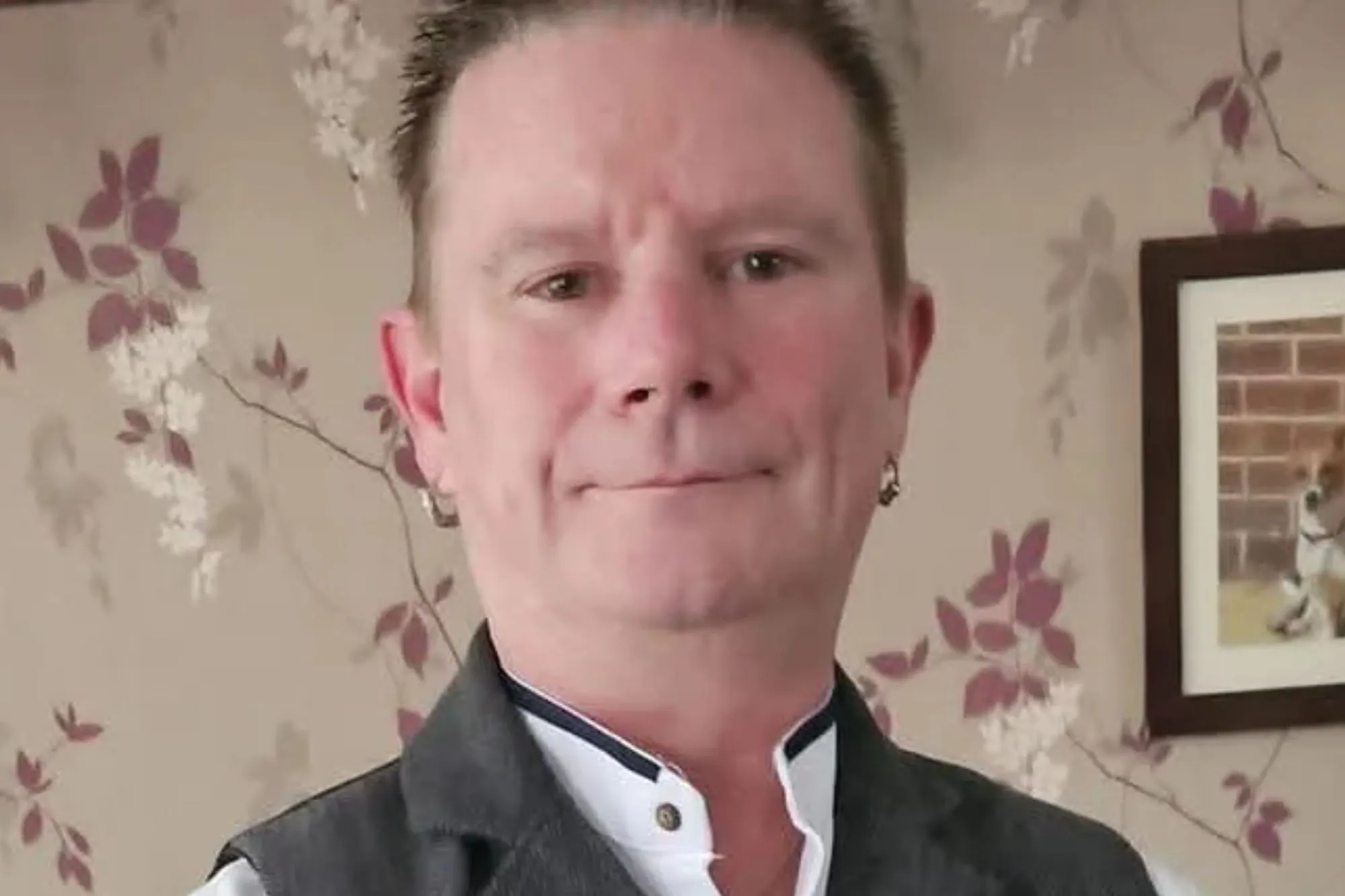 An image collage containing 1 images, Image 1 shows Portrait of Ian Jackson Winch, a man with short brown hair, wearing a white shirt and a gray waistcoat, standing in a room with floral wallpaper