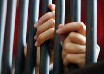 Close-up shot of women's hands in a jail.