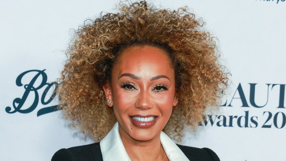 Mel B smiling with her curly hair framing her face.