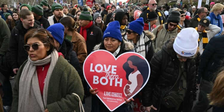 People hold signs at a pro-life March for Life rally in Washington, DC, on Jan. 23, 2026.