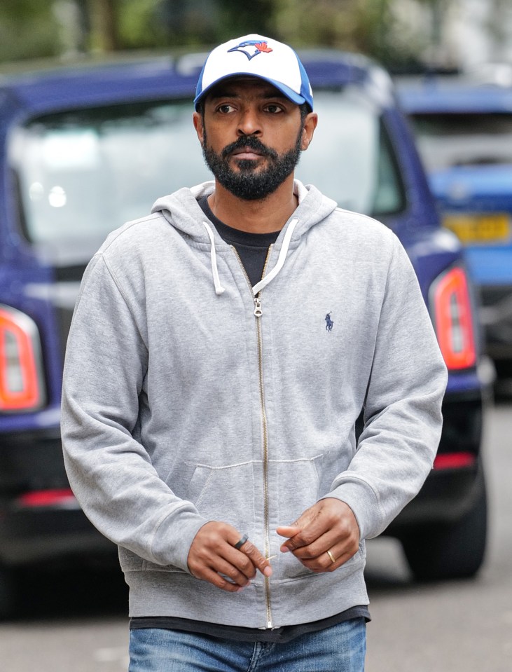 Noel Clarke in a grey hoodie and baseball cap walking in Kensington after his arrest.