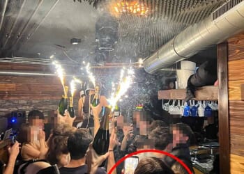 In a clip taken from the deadly night at Le Constellation in Crans-Montana, a woman, believed to be bar owner Jessica Moretti, can be seen in the foreground holding a champagne bottle topped with a lit sparkler in one hand and a phone in the other