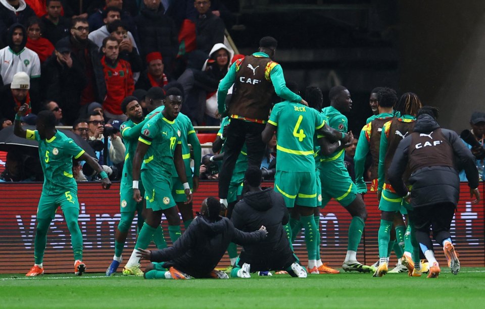 Senegal football players in green and yellow uniforms celebrating after winning the Africa Cup of Nations.