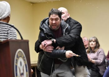 A man later identified as Anthony J. Kazmierczak, 55, is tackled after spraying a substance now believed to be apple cider vinegar at Democratic Rep. Ilhan Omar during a town hall she was hosting Tuesday in Minneapolis, Minnesota.
